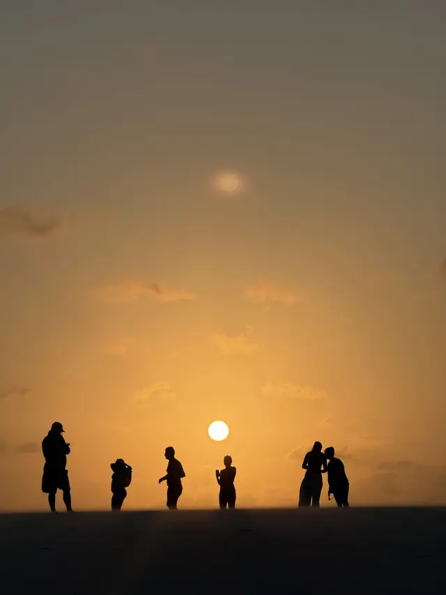 Silhuetas de viajantes ao pôr do sol nas dunas