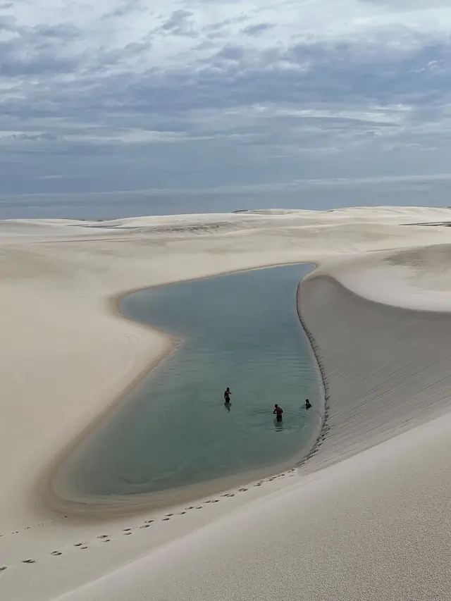 Vista elevada de lagoa entre dunas com banhistas