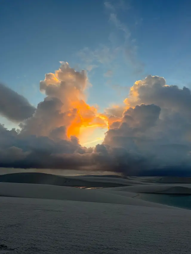 Nuvem iluminada pelo sol se pondo sobre as dunas